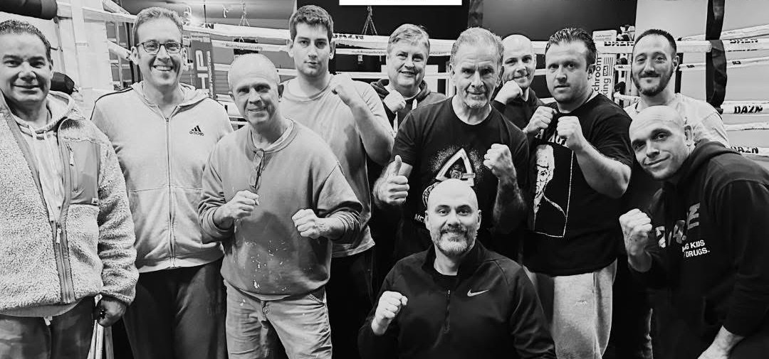 A group posing beside a boxing ring