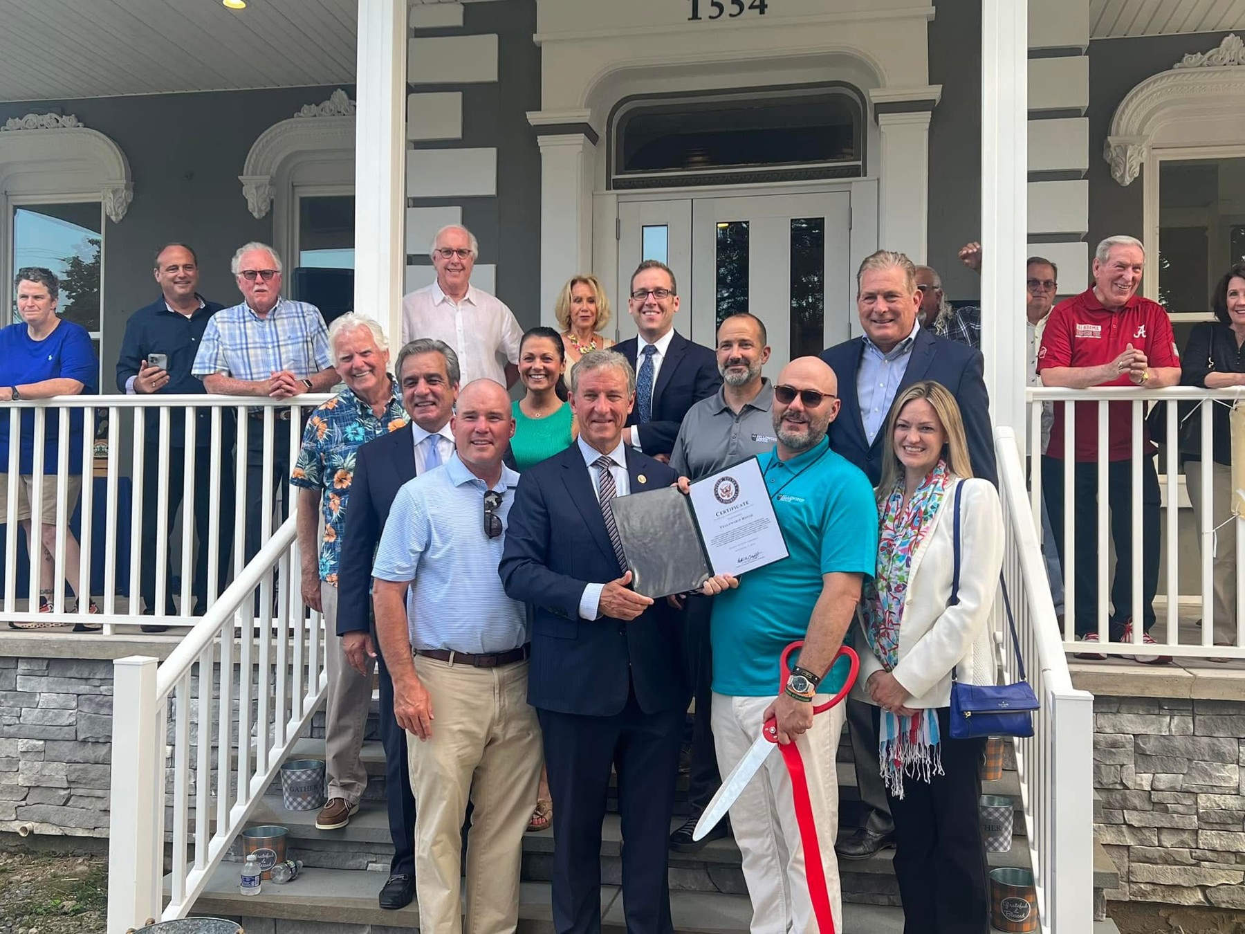 A ribbon-cutting gathering on the Fellowship House porch